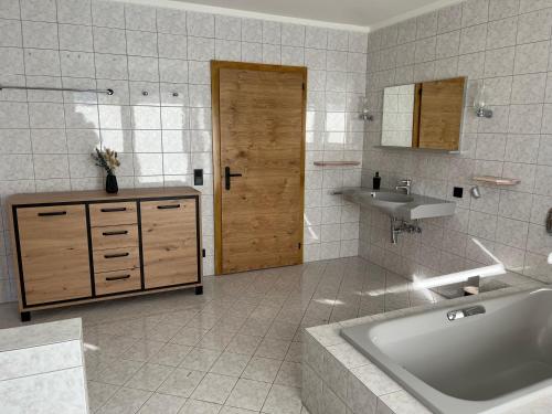 a bathroom with a tub and a sink and a door at Bergblick Appartements in Bad Gastein