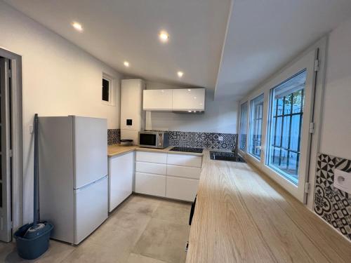  La cuisine est équipée de placards blancs et d'un réfrigérateur. dans l'établissement T2 cosy avec terrasse - 5 min des plages, à La Garde