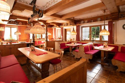 a restaurant with wooden tables and red chairs at Alpen Hotel Martin in Nesselwang