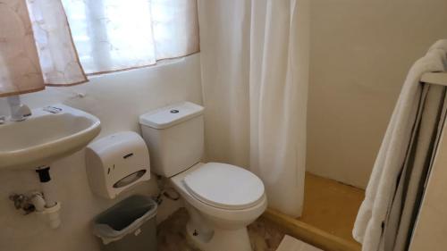 a white bathroom with a toilet and a sink at The Boat House in Boca Chica