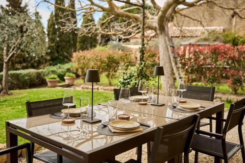 a wooden table with glasses and plates on it at Il Giardino del Cardinale - Deb'S Monticchiello in Monticchiello