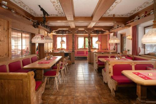 a restaurant with wooden tables and red chairs at Alpen Hotel Martin in Nesselwang