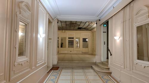 un couloir d'un immeuble avec des murs et des plafonds blancs dans l'établissement cosy appartement next to Louvre, à Paris