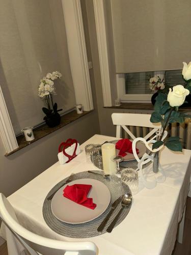 a white table with a white plate and red napkin at La Pause Roséeenne in Rousies