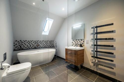 a bathroom with a tub and a toilet and a sink at Holly Tree Cottage in Dornoch