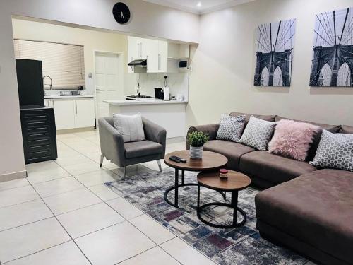 a living room with a couch and a table and a kitchen at Sweet Daisies Apartment in Mbabane