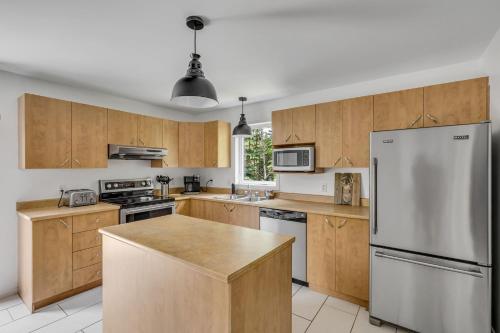 a kitchen with wooden cabinets and a stainless steel refrigerator at Initial Yellow Lac-Beauport in Sainte Brigitte de Laval