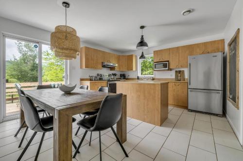 a kitchen with a table and chairs and a refrigerator at Initial Yellow Lac-Beauport in Sainte Brigitte de Laval