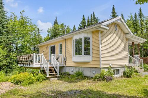 a small yellow house with a porch and a deck at Initial Yellow Lac-Beauport in Sainte Brigitte de Laval