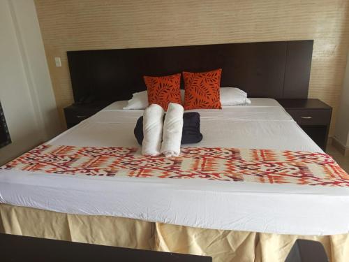 a bedroom with a bed with white sheets and orange pillows at HOTEl TANGARA in Pereira