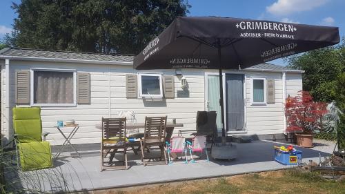 a patio with a table and chairs and an umbrella at Logement vacances Yvoir avec piscine et deux chambres in Yvoir