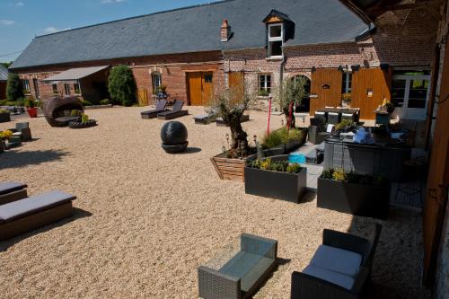 a courtyard with chairs and plants in front of a building at Le Prieuré Chambres d'hôtes in Sainte-Preuve