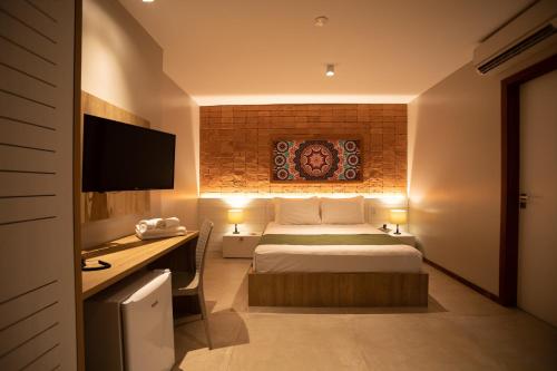 a bedroom with a bed and a desk with a television at Bravo Pousada Design in Cabo Frio