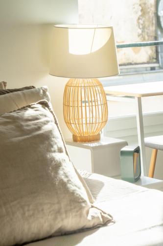 une lampe assise à côté d'un lit avec un oreiller dans l'établissement Appartement lumineux & calme en centre ville, à La Rochelle