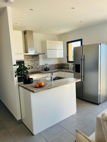 Una cocina con un refrigerador y una encimera con naranjas encima. en Appartement 4 personnes tout confort avec vue panoramique sur MER, en Port-Vendres