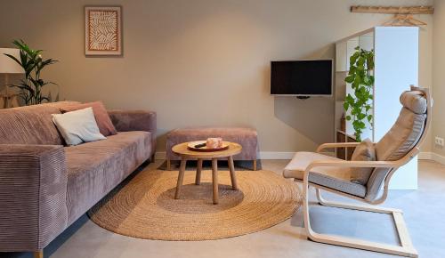 a living room with a couch and a table and a chair at Zilt aan Zee in Egmond aan Zee