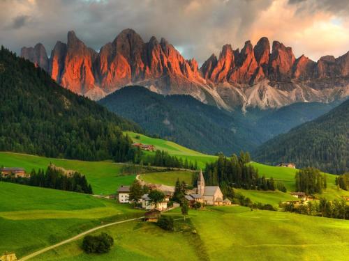 a green field with a house in front of a mountain at Dolomiten Home in Villnoss
