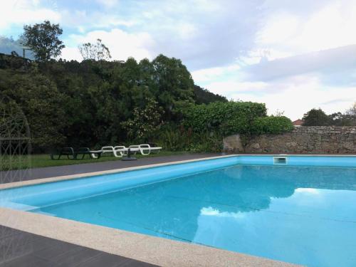 a blue swimming pool with two chairs and a wall at Maison traditionnelle Areosa in Viana do Castelo