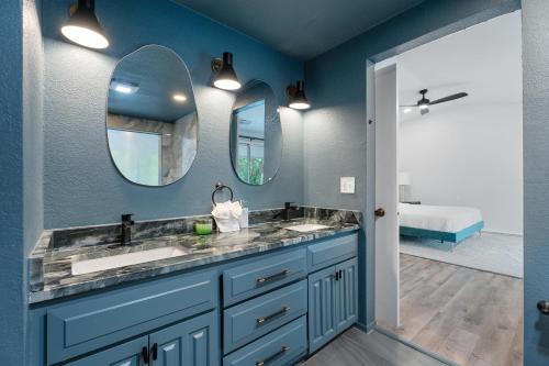 a blue bathroom with two sinks and two mirrors at 5br Getaway Near Plaza Dist Patio & Lounge #mr in Warr Acres