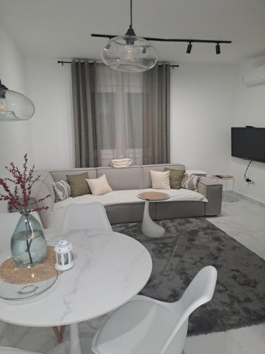 バニャ・コヴィリャチャにあるApartman Simonの白いリビングルーム(ソファ、テーブル付)