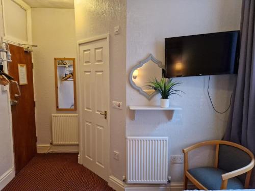 a hallway with a tv on a wall and a chair at Stafford House in Blackpool