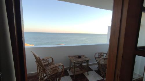 a balcony with chairs and a table and the ocean at Serenity Lodge in Sharm El Sheikh