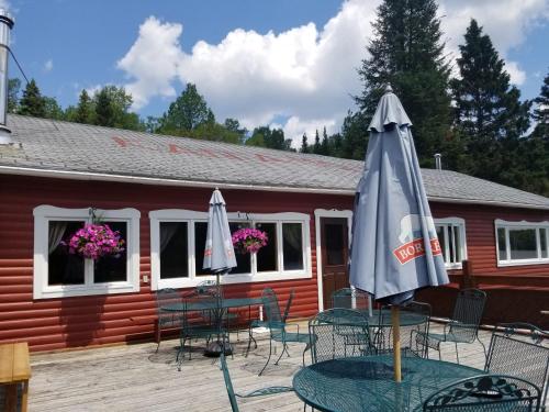 a patio with tables and chairs and an umbrella at Kan-à-Mouche Pourvoirie Auberge et Chalets in Saint-Michel-des-Saints