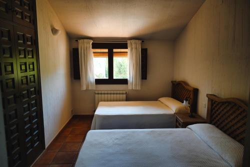 a small room with two beds and a window at Casa Rural Nelia in Villalba de la Sierra