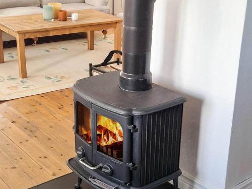 a black stove in a living room with a table at 8 person holiday home in SKIVARP in Skivarp