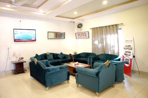a living room with blue couches and a table at Royalz Hotel in Lahore