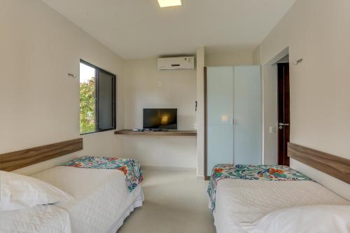 a bedroom with two beds and a television in it at Hotel Sete Ilhas in Florianópolis