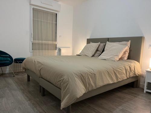 - une chambre avec un grand lit et une chaise bleue dans l'établissement ApptT2 neuf Port de Saint Valéry sur Somme, à Pinchefalise