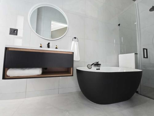 a bathroom with a black tub and a mirror at The Curve in Dullstroom