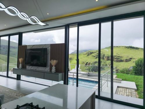 a living room with a tv and large glass windows at The Curve in Dullstroom