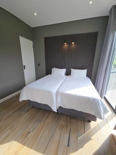a bedroom with a large bed with white sheets at The Curve in Dullstroom