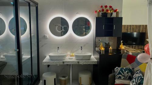 a bathroom with two sinks on a counter with mirrors at SUITE SOLIE SPA Wintzenheim in Wintzenheim