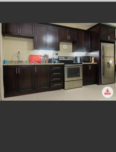 Una cocina con gabinetes de madera y un refrigerador de acero inoxidable. en thestartree, en Kingston