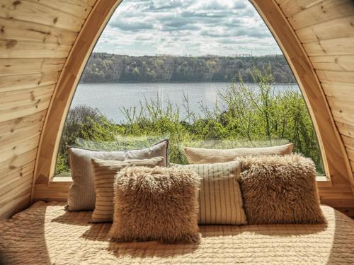 a bed with pillows in a room with a large window at Bramslev Bakker Naturhotel in Hobro