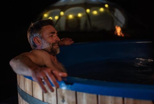 a man in a bath tub with a fire in the background at Bramslev Bakker Naturhotel in Hobro