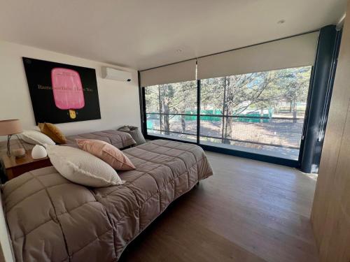a bedroom with a large bed with a large window at Casa entre pinos in La Florida