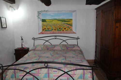 1 dormitorio con 1 cama con una pintura en la pared en Armaiolo Relax, en Rapolano Terme