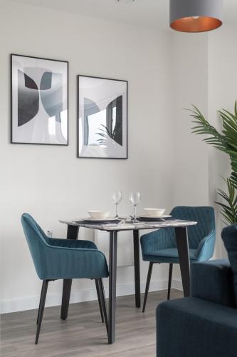 a dining room with a table and blue chairs at 31 Grand Court - Lovely Home Near Canal, Park, & Central MK in Milton Keynes