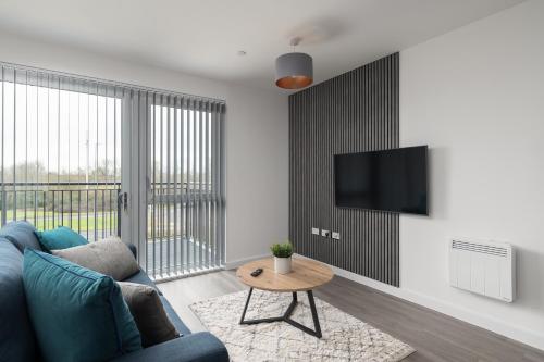 a living room with a blue couch and a table at 31 Grand Court - Lovely Home Near Canal, Park, & Central MK in Milton Keynes