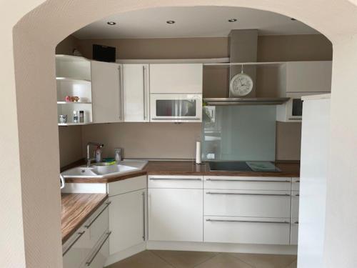 a kitchen with white cabinets and a clock on the wall at Tolle Wohnung in Taunusstein in Taunusstein