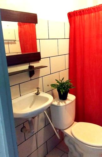 a bathroom with a toilet and a sink and a red shower curtain at pousada mar azul in Salvador