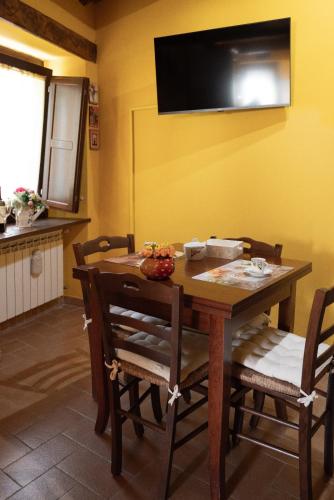 a dining room table with chairs and a television on the wall at appartamento LE LOGGE in Montefiascone