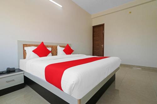 a bedroom with a large white bed with red pillows at Hotel O Safari Inn in Hāpur