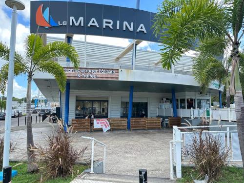 a marina building with palm trees in front of it at Goldy House, logement vue mer , jacuzzi 10min port et aéroport in Baimbridge