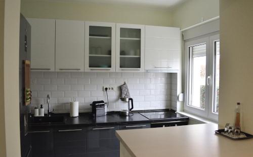 a kitchen with white cabinets and a black counter top at AeroVista Apartment in Surčin