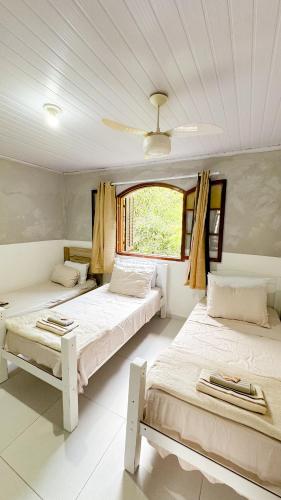deux lits dans une chambre avec une fenêtre dans l'établissement Casa na Vila do Abraão - Ilha Grande, à Angra dos Reis